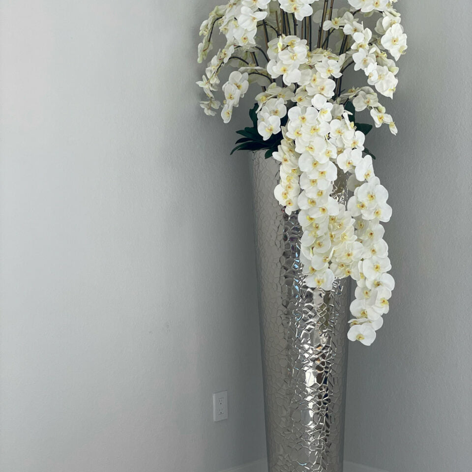 Kaskadierende Phalaenopsis-Orchideen in extrahoher gehämmerter Vase